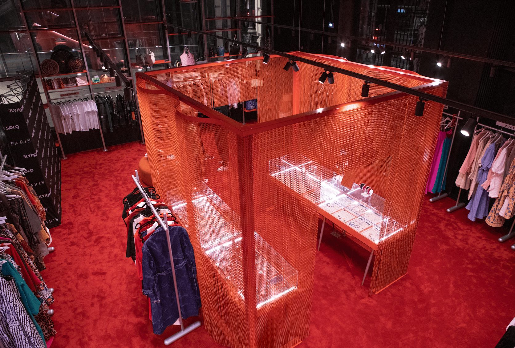 Stylish boutique interior showcasing vibrant red decor and illuminated display cases at Flying Solo Paris.