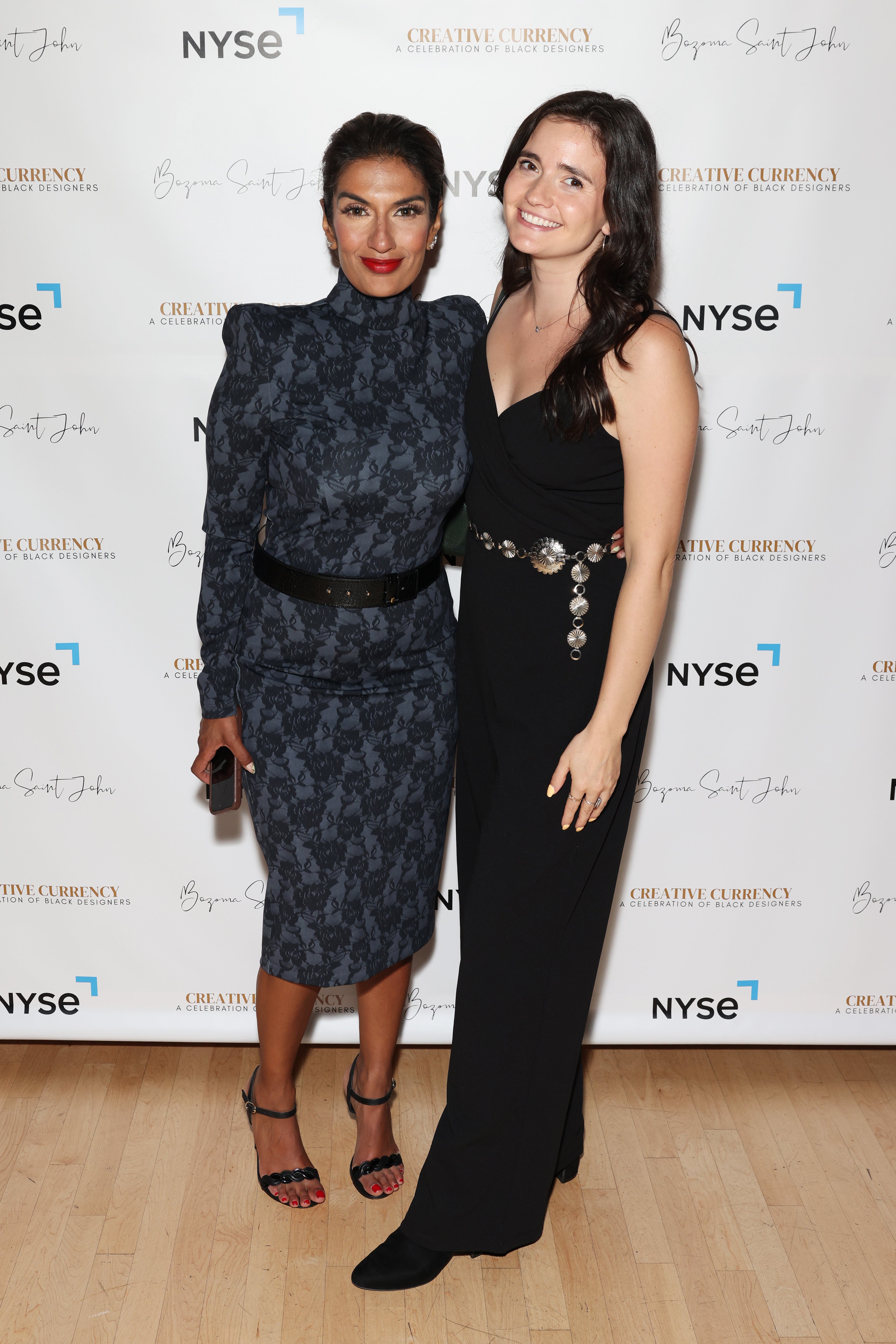 Two women posing, one in Black Widow dress and the other in a sleek black gown.