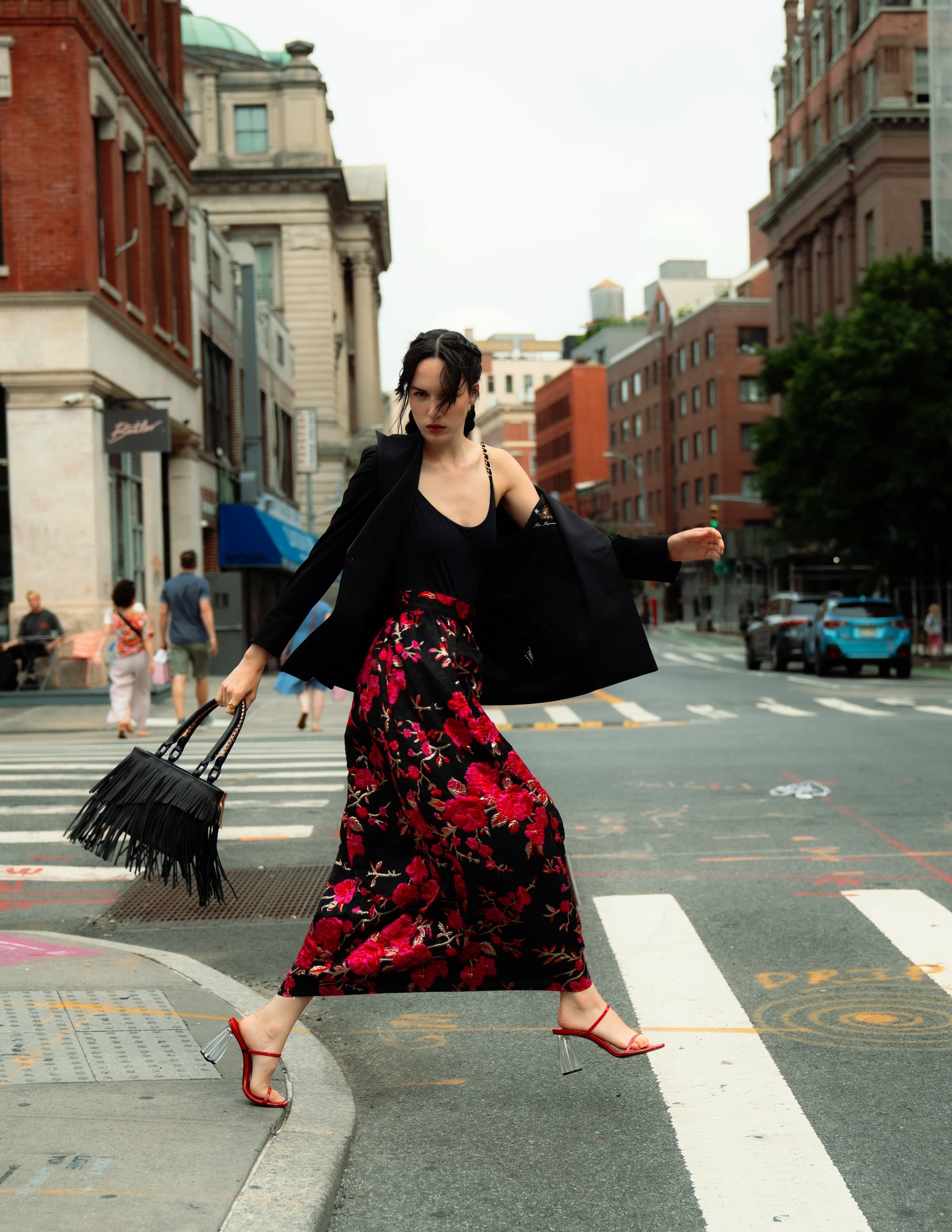 Woman in Starry Night blazer and floral maxi dress walking confidently across a city street.