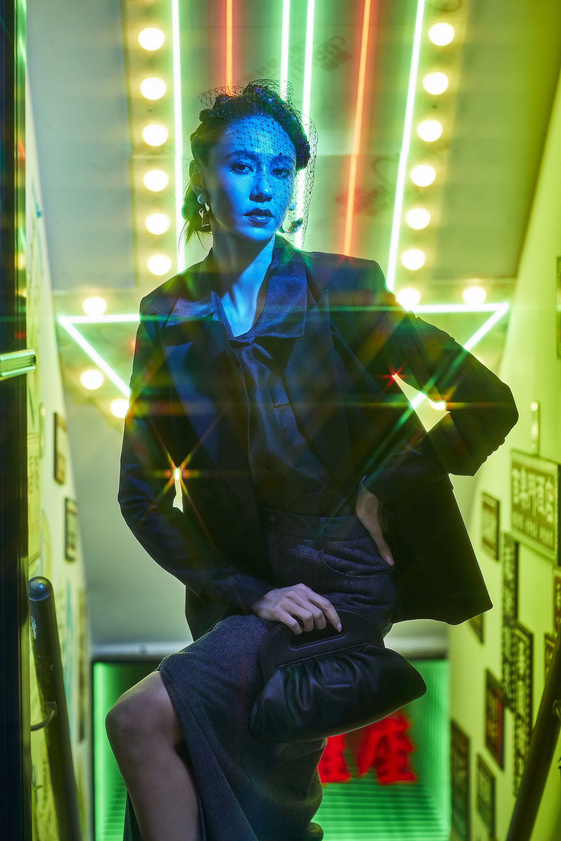 Model in Starry Night blazer outfit poses on stairs illuminated by vibrant neon lights and reflections.