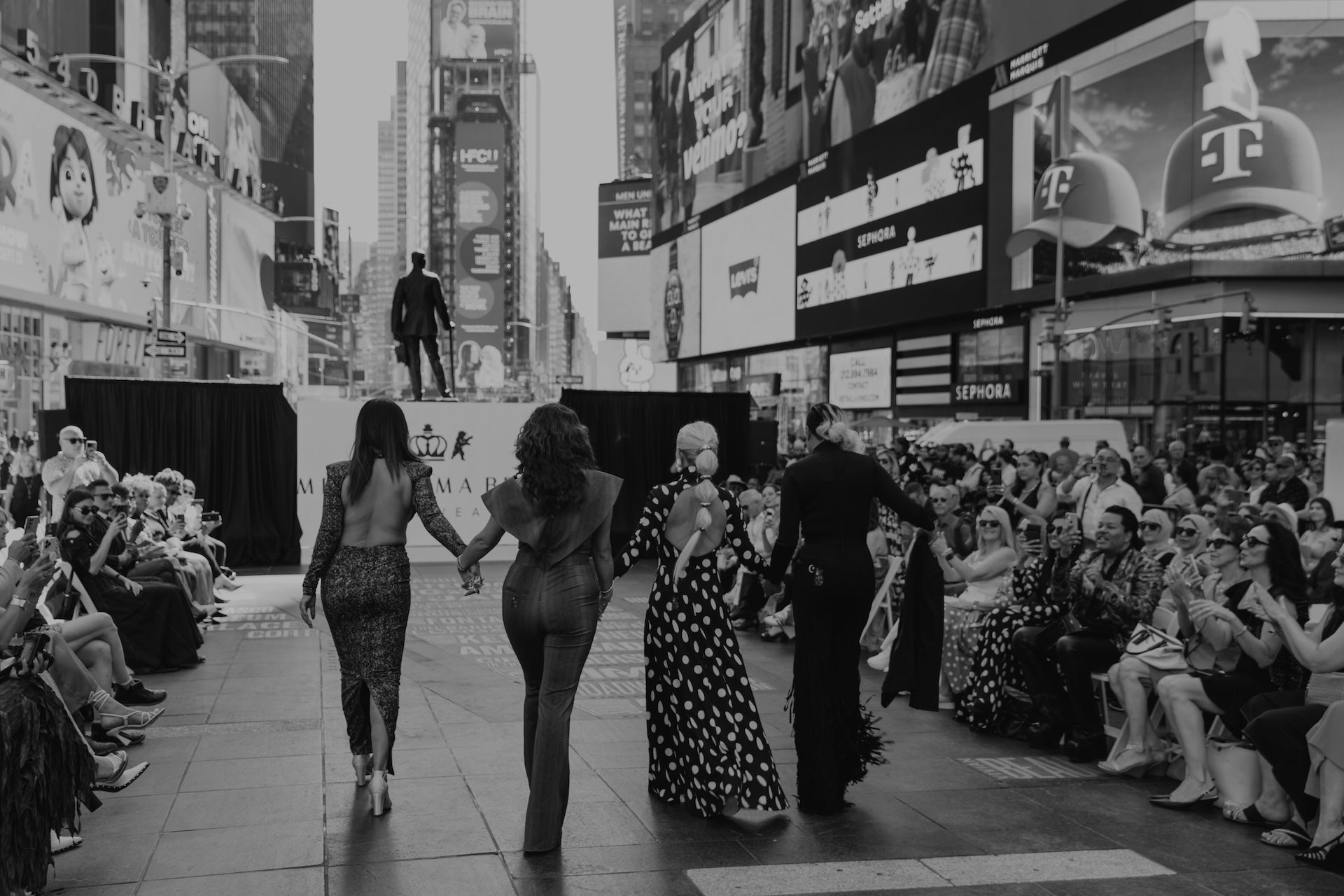 Models walking the runway in Times Square with an audience applauding, showcasing Black Diamond, Supernova, Sexy Day, and Fringy Baby in a vibrant city setting.