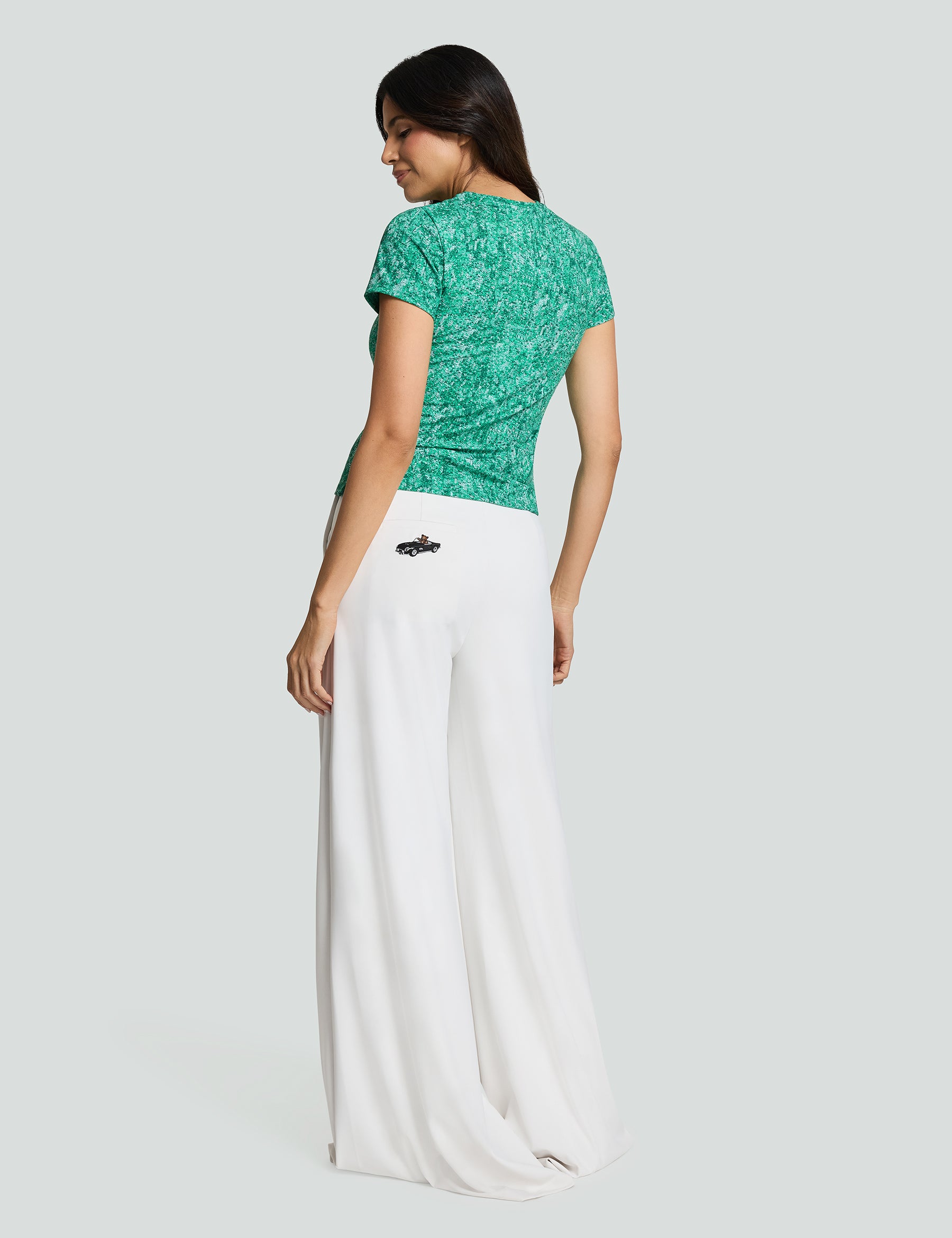 Woman wearing the Signature Luxe Tee in Verde Mi Amor, paired with white pants, showcasing an elegant and casual style.