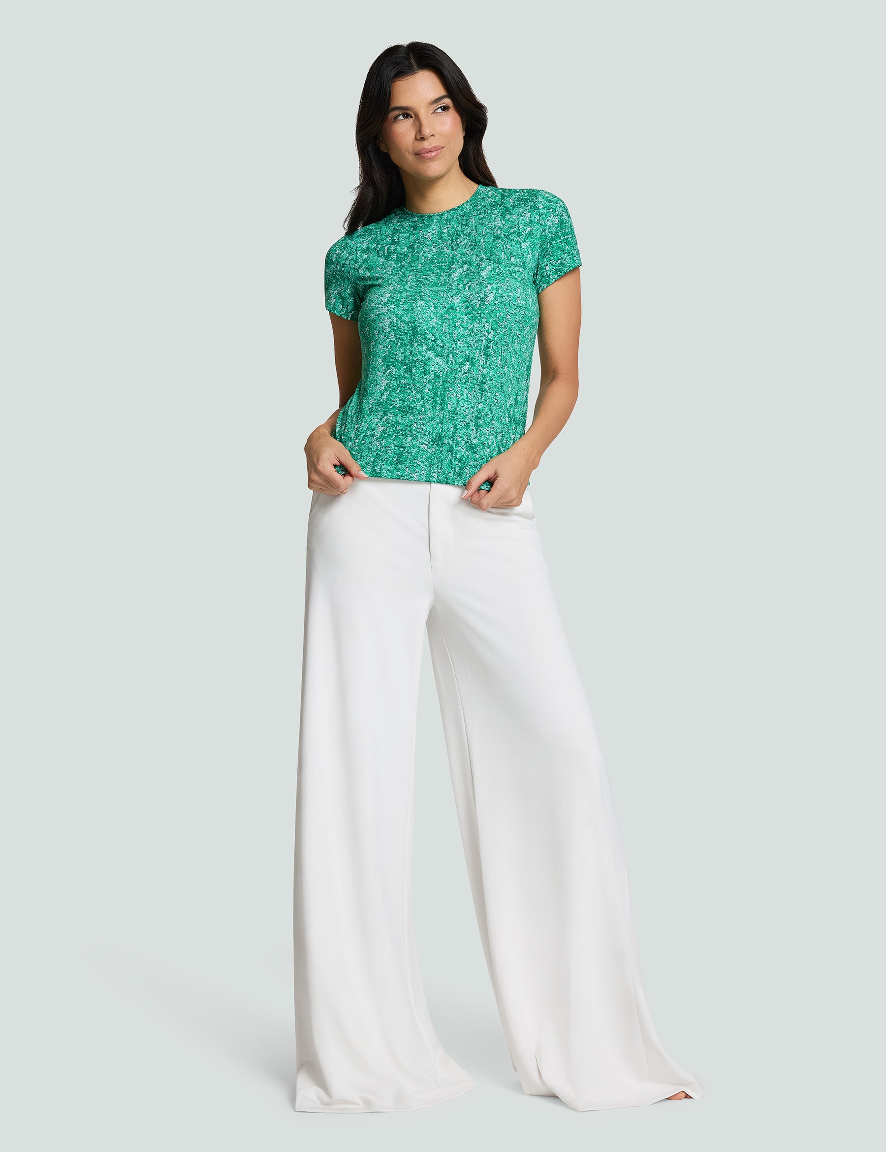 Model wearing Signature Luxe Tee in Verde Mi Amor, paired with white wide-leg pants for a stylish, casual look.