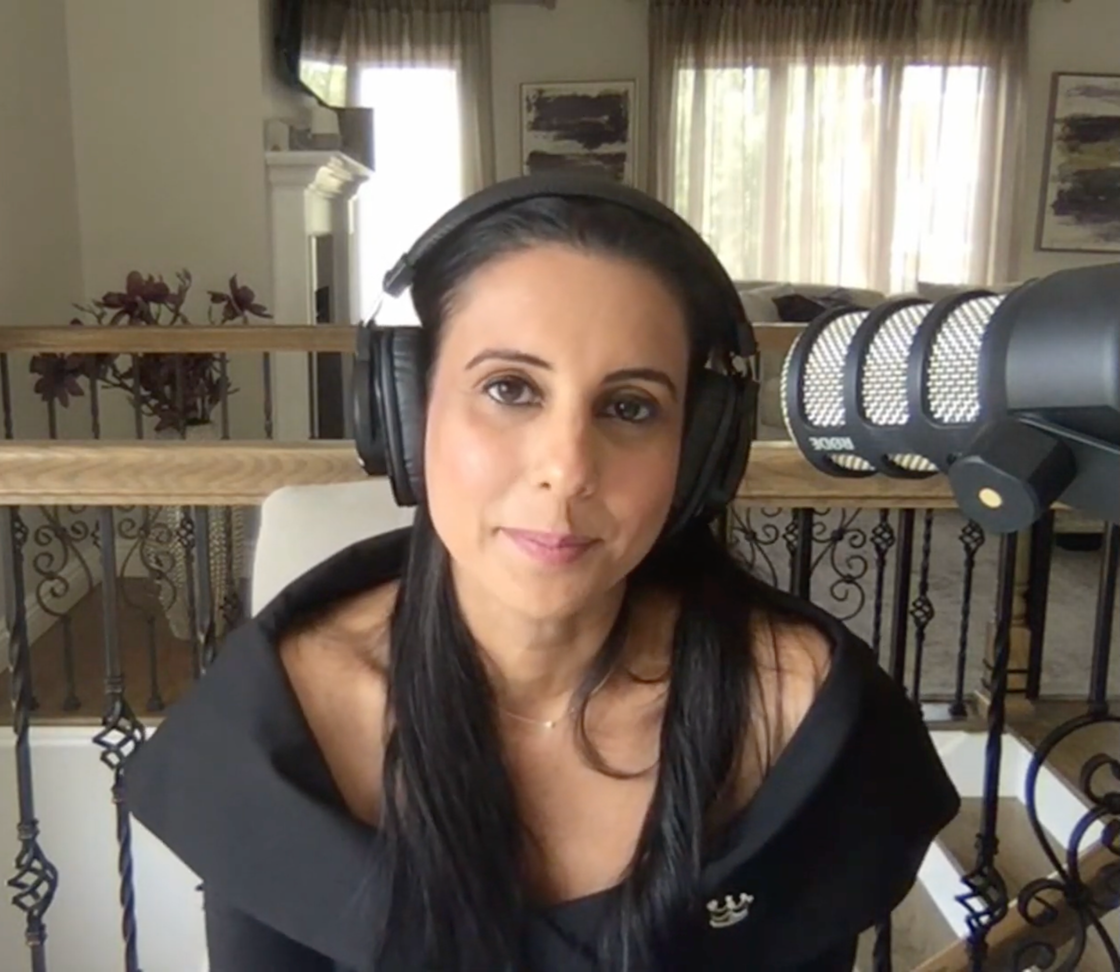 Woman with headphones in Tux All Day All Night Set, sitting in a modern room with a microphone nearby.