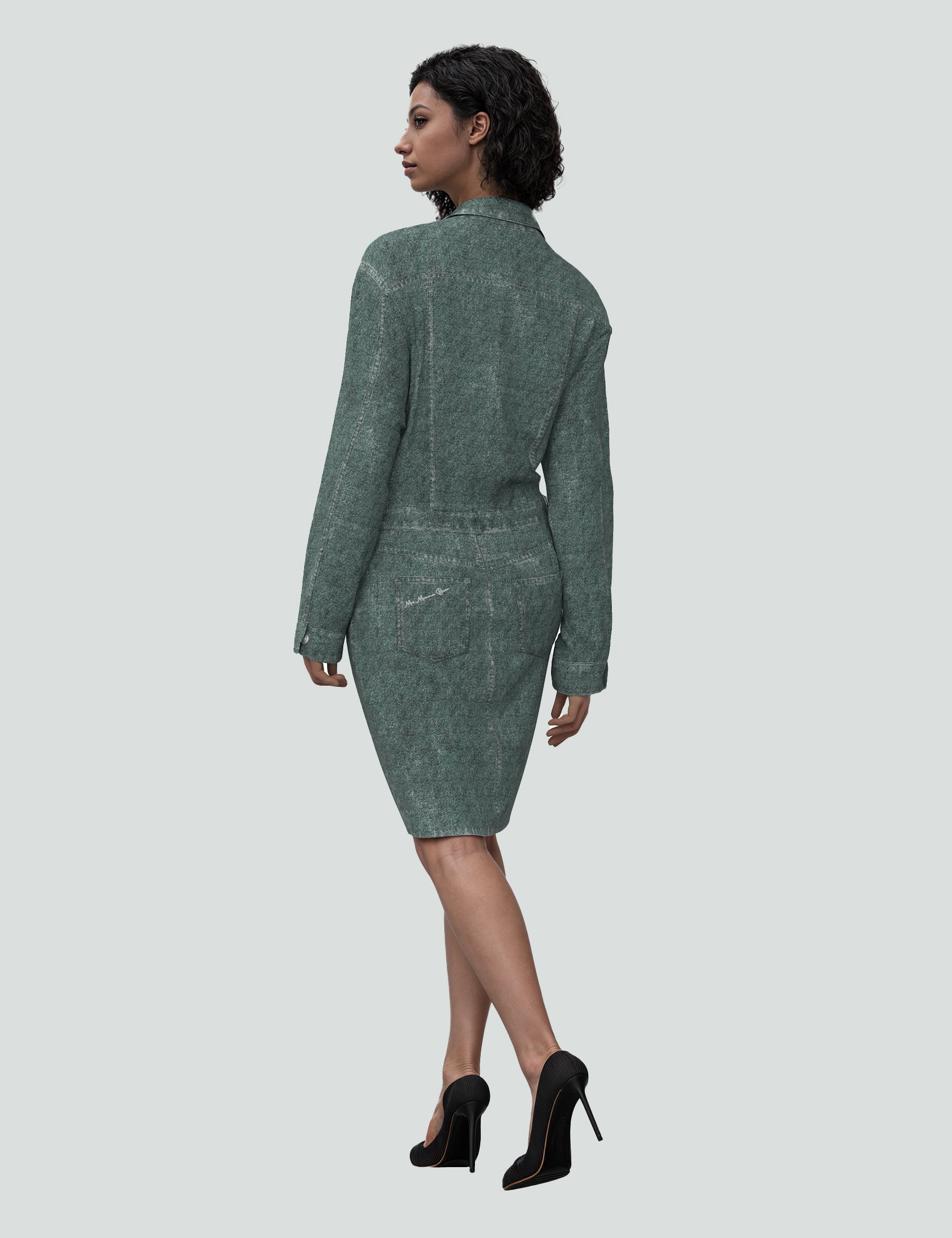 Back view of the Huntress green denim mini dress, stylishly paired with black heels, showcasing modern fashion.